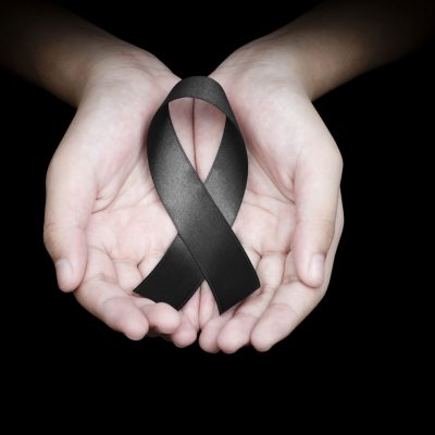 Quelle: #160526015 Hand holding black ribbon on black background mourning awareness sign © Love the wind | fotolia.com